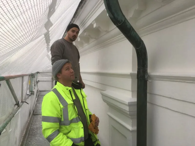 Två medarbetare vid en fasad under renovering