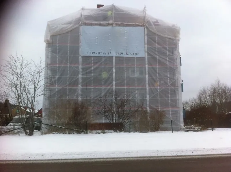 Byggnad inklädd i väderskydd under fasadrenovering